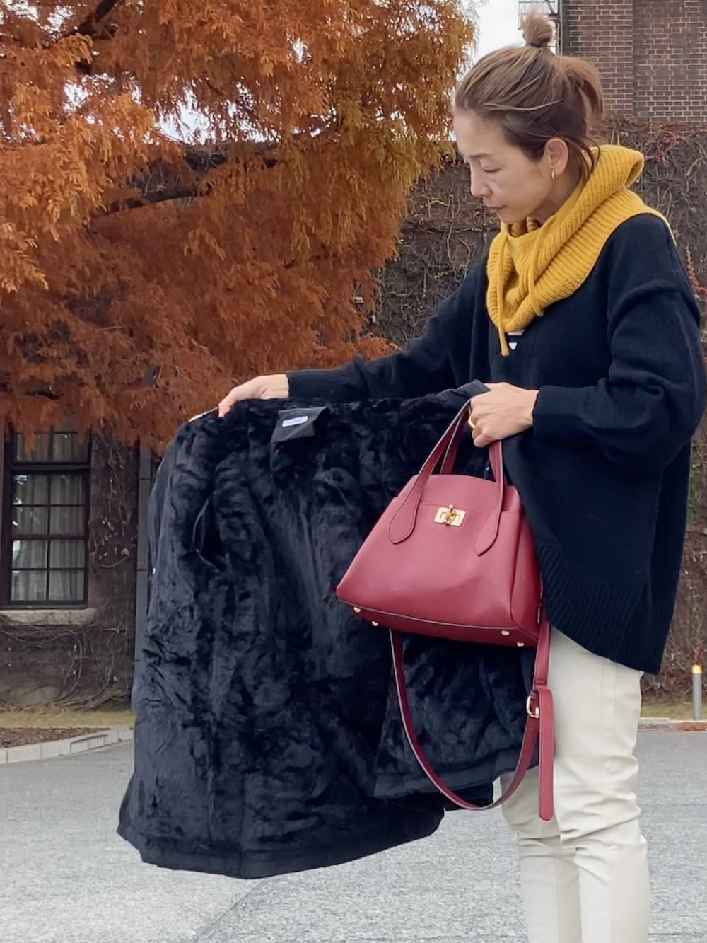 ブラック系のブルゾン、ブラック系のニット/セーター、ホワイト系のパンツを着用したレディースの冬コーディネートの4枚目の写真