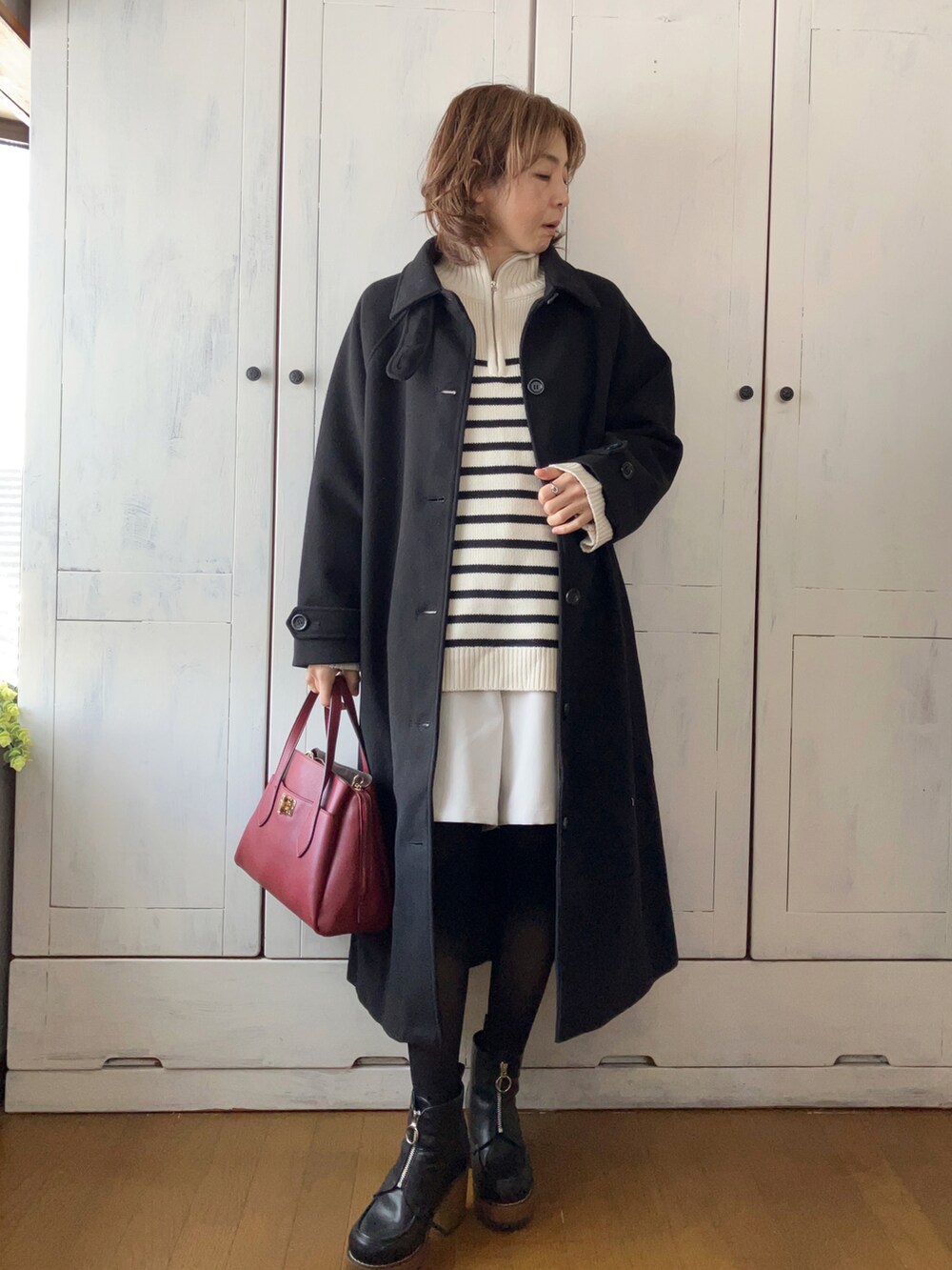 ブラック系のステンカラーコート、ホワイト系のニット/セーター、ベージュ系のその他パンツを着用したレディースの冬コーディネートの2枚目の写真