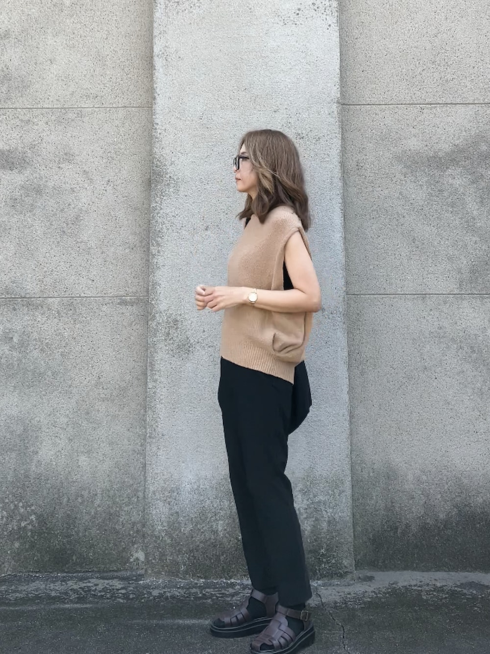 ベージュ系のベスト、ブラック系のパンツ、ブラック系のショルダーバッグを着用したレディースの夏コーディネートの3枚目の写真
