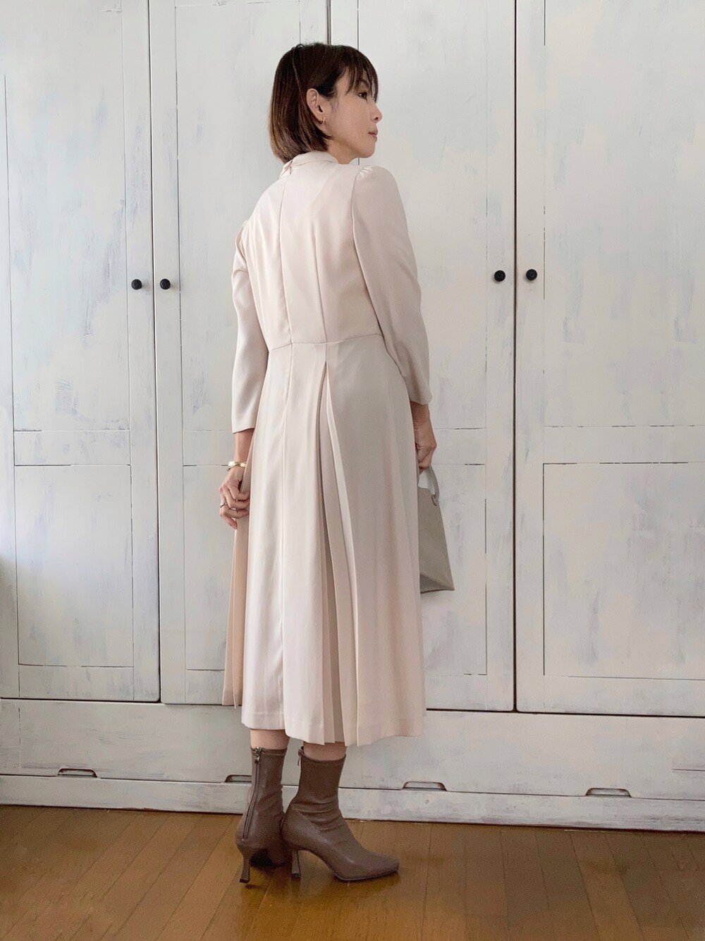 ベージュ系のワンピース、ブルー系のチェスターコート、ベージュ系のショルダーバッグを着用したレディースの冬コーディネートの2枚目の写真