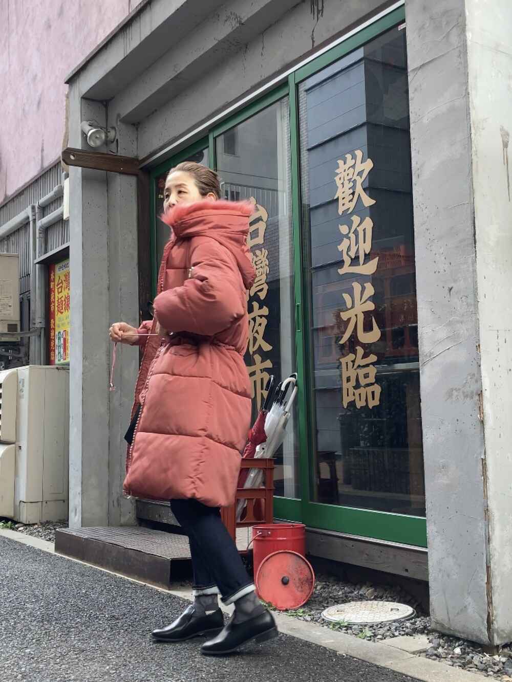 レッド系のダウンジャケット/コート、ブルー系のデニムパンツ、ブラック系のローファーを着用したレディースの冬コーディネートの3枚目の写真