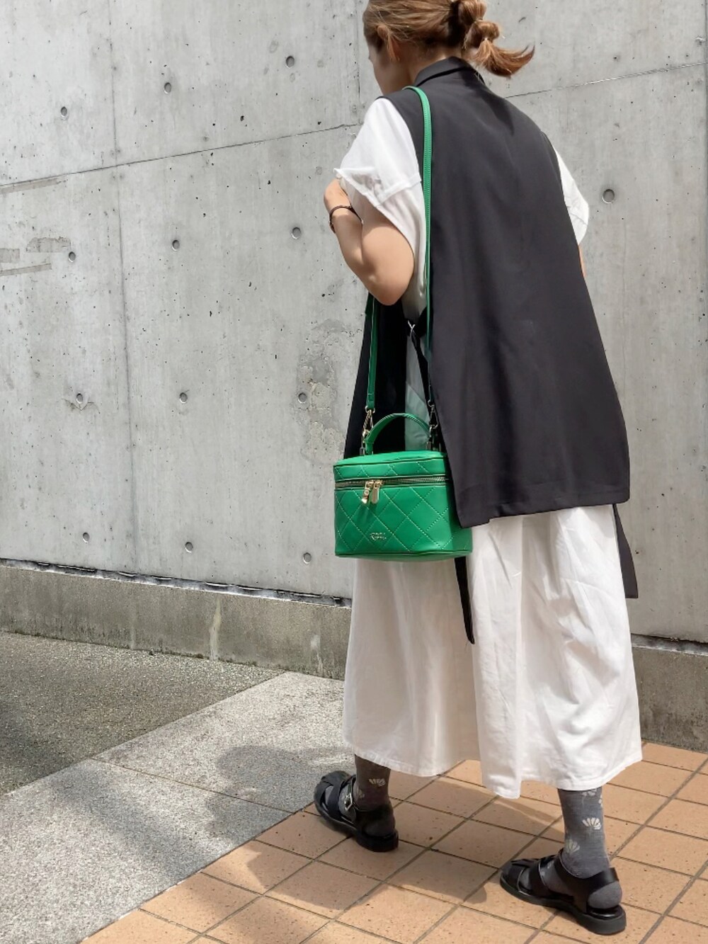 ブラック系のベスト、ホワイト系のワンピース、グリーン系のショルダーバッグを着用したレディースの夏コーディネートの3枚目の写真