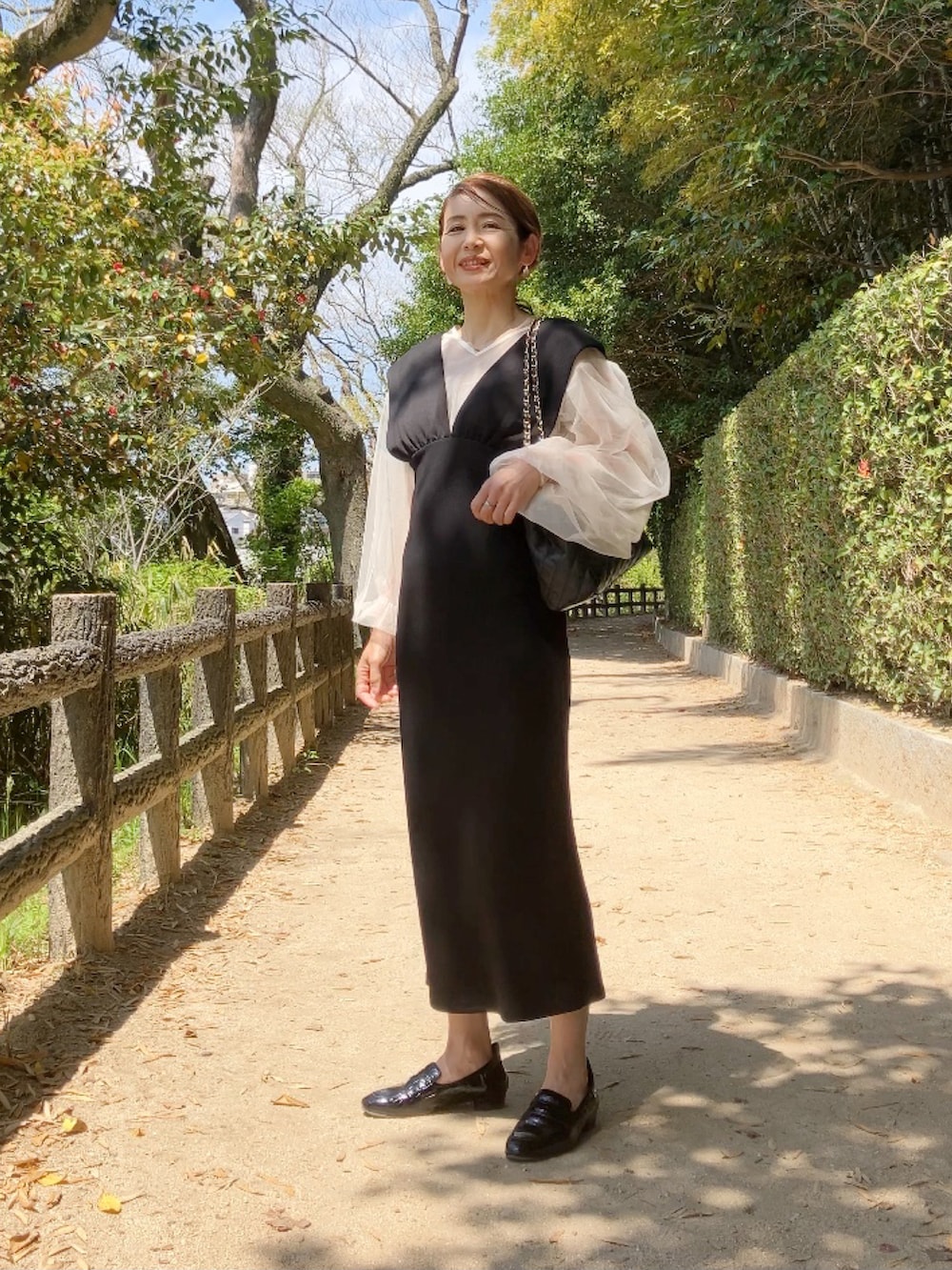 ブラック系のワンピース、ホワイト系のシャツ/ブラウス、ブラック系のボストンバッグを着用したレディースの春コーディネートの2枚目の写真