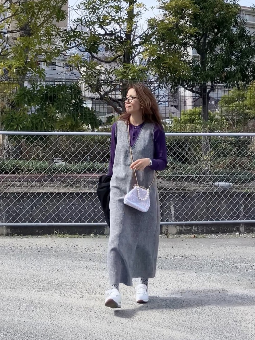 グレー系のワンピース、ホワイト系のハンドバッグ、ホワイト系のスニーカーを着用したレディースの冬コーディネートの2枚目の写真