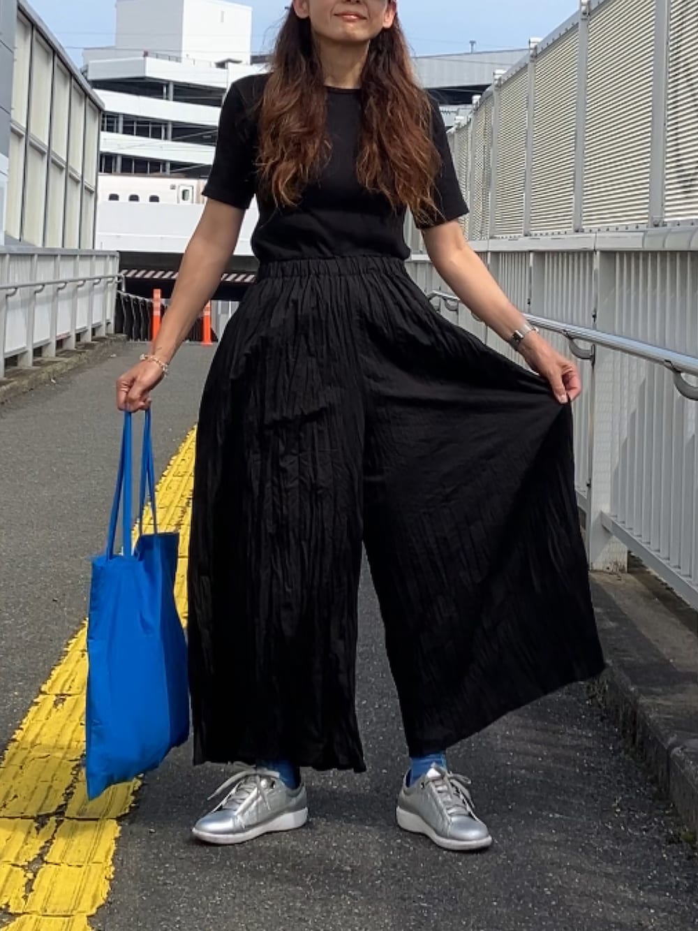 ブラック系のパンツ、ブラック系のTシャツ/カットソー、ブルー系のキャップを着用したレディースの夏コーディネートの4枚目の写真