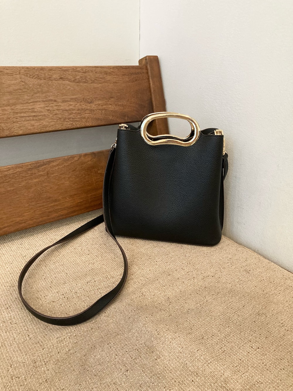 ブラック系のハンドバッグ、ホワイト系のスカート、ホワイト系のベストを着用したレディースの春コーディネートの4枚目の写真