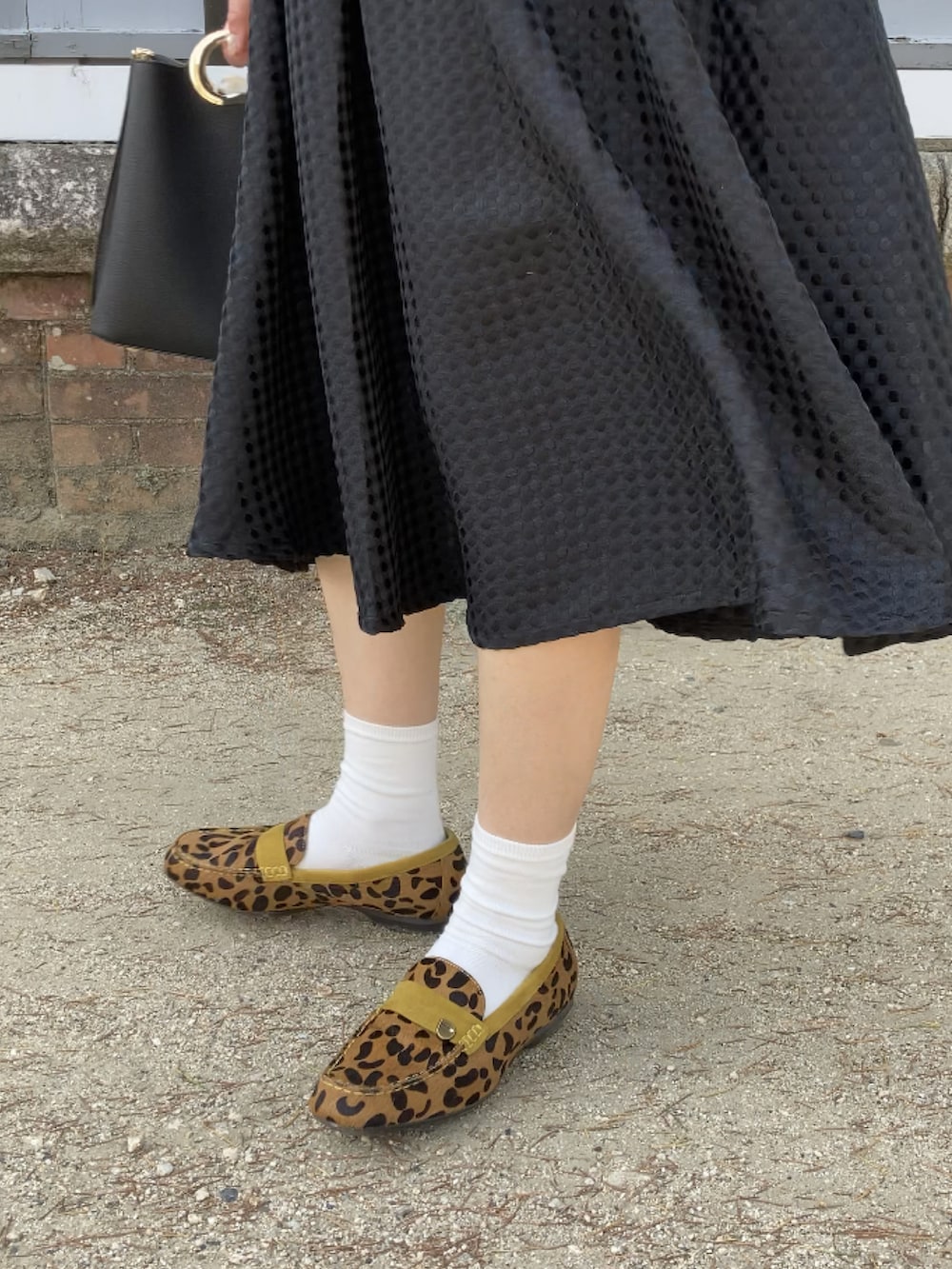 ベージュ系のローファー、ブラック系のハンドバッグ、ブラック系のスカートを着用したレディースの春コーディネートの4枚目の写真