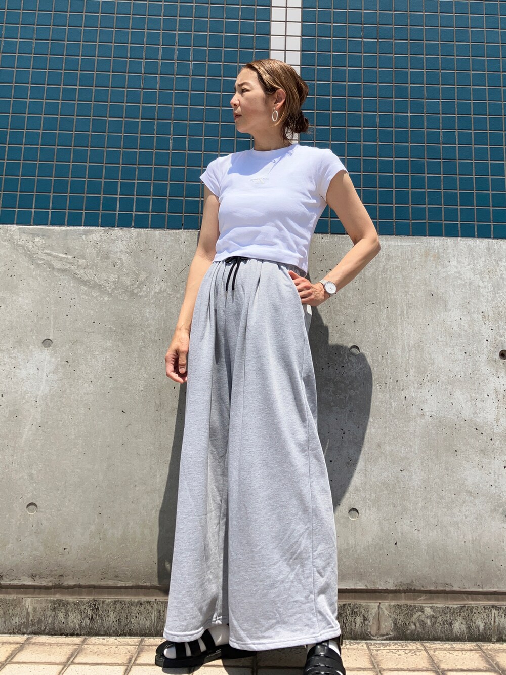 ホワイト系のTシャツ/カットソー、グレー系のスウェットパンツ、ブラック系のサンダルを着用したレディースの春コーディネートの2枚目の写真
