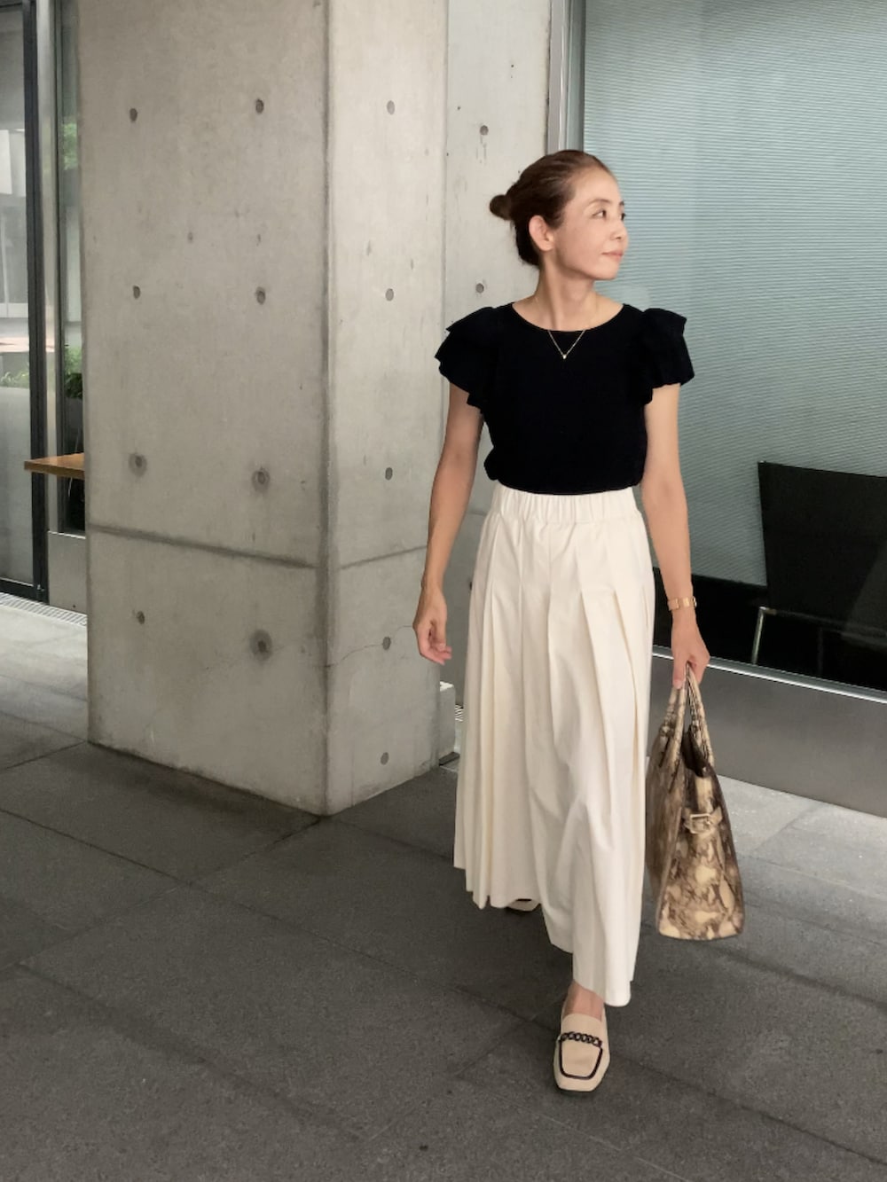 ホワイト系のスカート、ベージュ系のシューズ、ブラック系のニット/セーターを着用したレディースの夏コーディネートの4枚目の写真