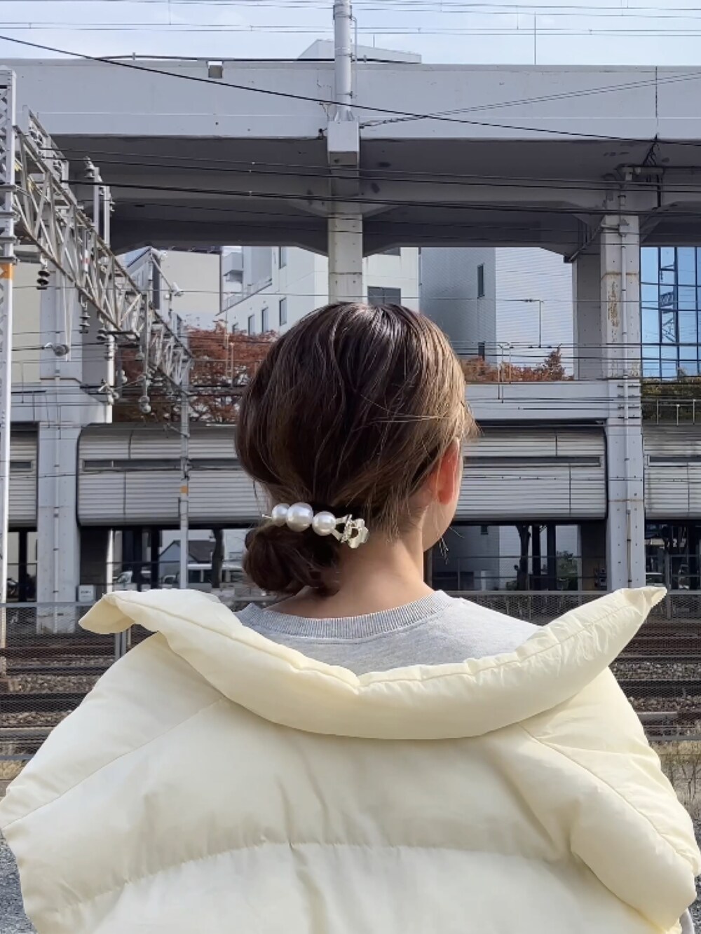 グレー系のスウェット、ホワイト系のダウンベスト、ホワイト系のバレッタ/ヘアクリップを着用したレディースの秋コーディネートの3枚目の写真