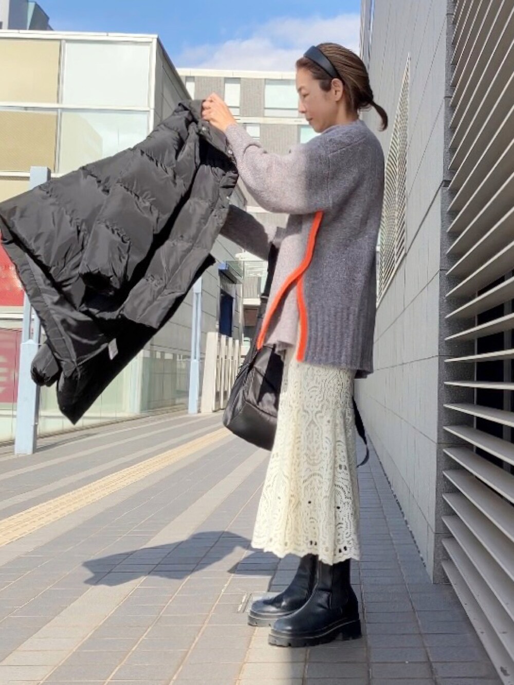 グレー系のニット/セーター、ホワイト系のスカート、ブラック系のブーツを着用したレディースの冬コーディネートの3枚目の写真