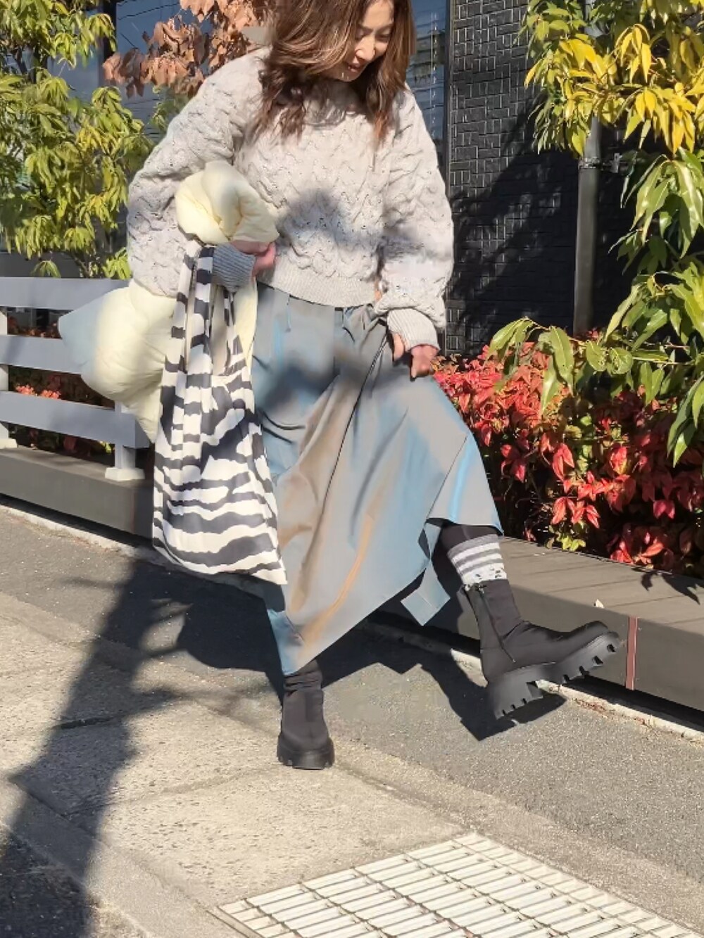 ベージュ系のニット/セーター、グリーン系のスカート、ホワイト系のダウンベストを着用したレディースの冬コーディネートの4枚目の写真