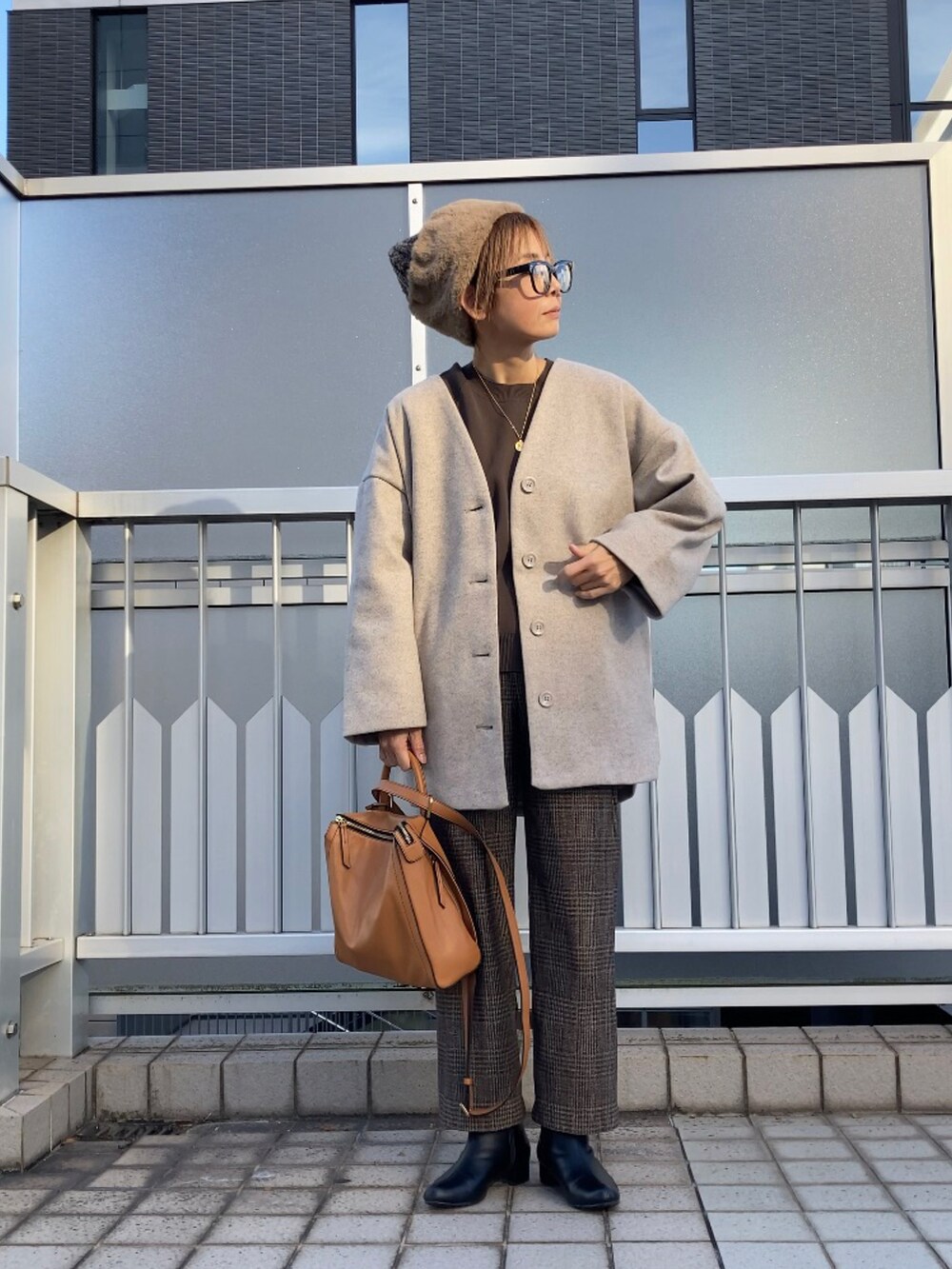 ベージュ系のノーカラーコート、ブラウン系のニット/セーター、ブラウン系のパンツを着用したレディースの秋コーディネートの3枚目の写真