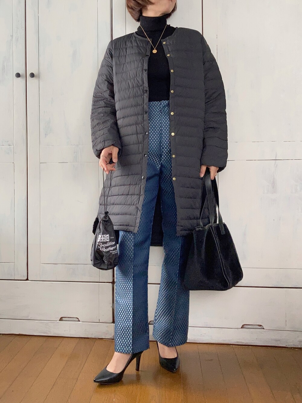 ブラック系のダウンジャケット/コート、ブラック系のニット/セーター、ブラック系のトートバッグを着用したレディースの秋コーディネートの2枚目の写真