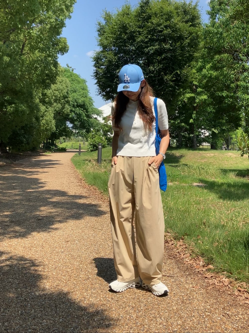 ベージュ系のパンツ、ホワイト系のポロシャツ、ブルー系のトートバッグを着用したレディースの夏コーディネートの4枚目の写真