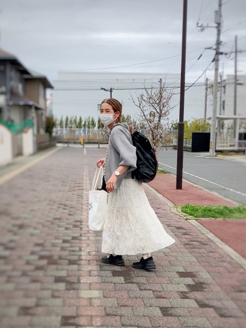 グレー系のカーディガン/ボレロ、ホワイト系のワンピース、ブラウン系のバックパック/リュックを着用したレディースの春コーディネートの3枚目の写真