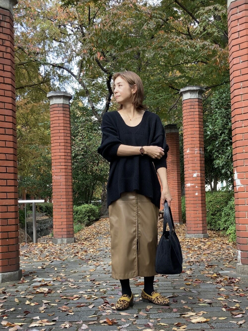 ブラック系のニット/セーター、ブラウン系のスカート、ブラック系のトートバッグを着用したレディースの秋コーディネートの4枚目の写真