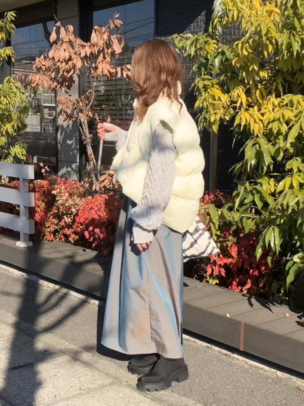 ベージュ系のニット/セーター、グリーン系のスカート、ホワイト系のダウンベストを着用したレディースの冬コーディネートの5枚目の写真