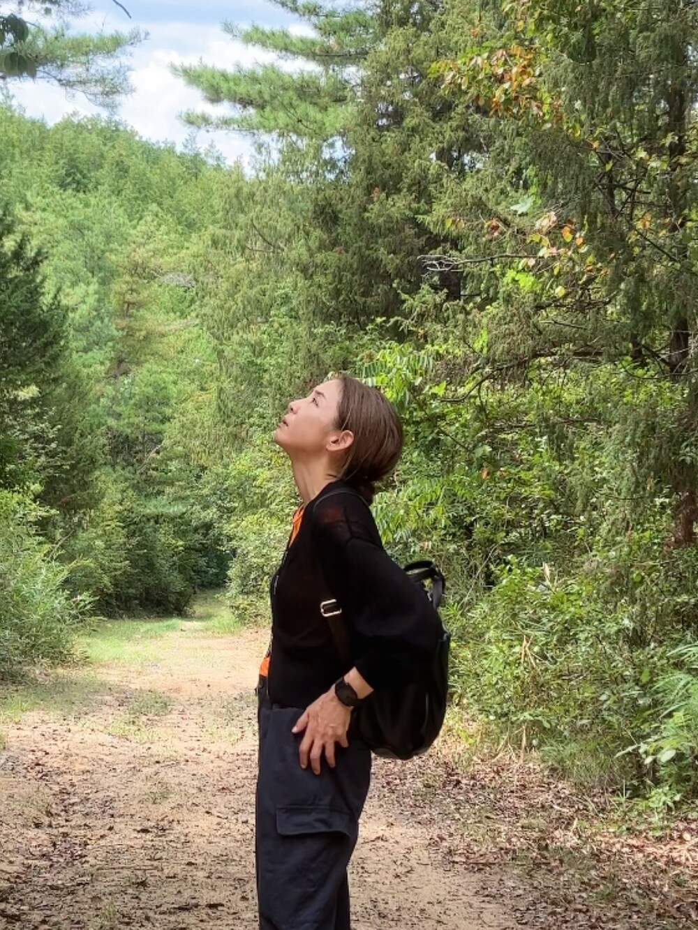 オレンジ系のTシャツ/カットソー、ブラック系のカーディガン/ボレロ、ブラック系のカーゴパンツを着用したレディースの秋コーディネートの4枚目の写真