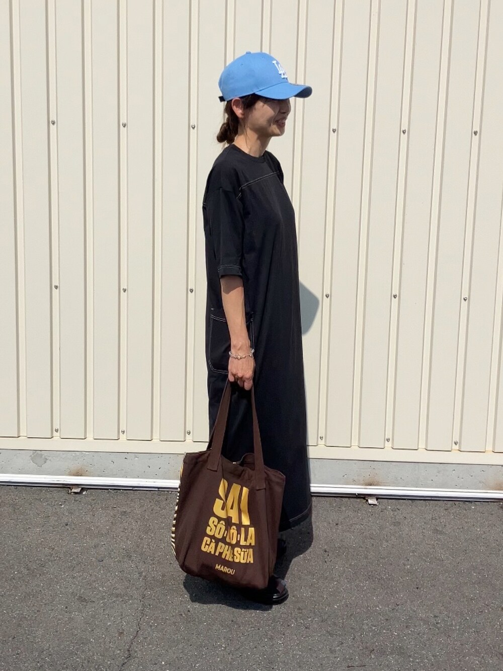 ブラック系のワンピース、ホワイト系のパンツ、ブルー系のキャップを着用したレディースの夏コーディネートの4枚目の写真