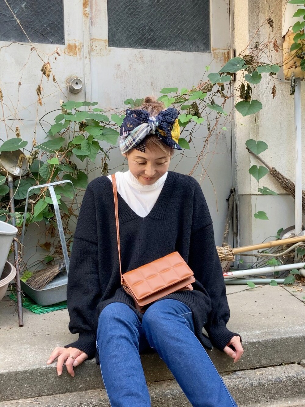 ブラック系のニット/セーター、ブルー系のデニムパンツ、ベージュ系のシューズを着用したレディースの秋コーディネートの3枚目の写真