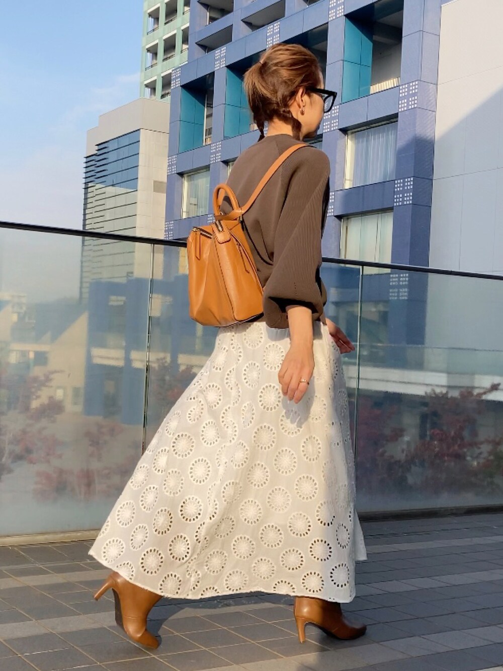 ブラウン系のニット/セーター、イエロー系のバックパック/リュック、ホワイト系のワンピース/ドレスを着用したレディースの秋コーディネートの3枚目の写真