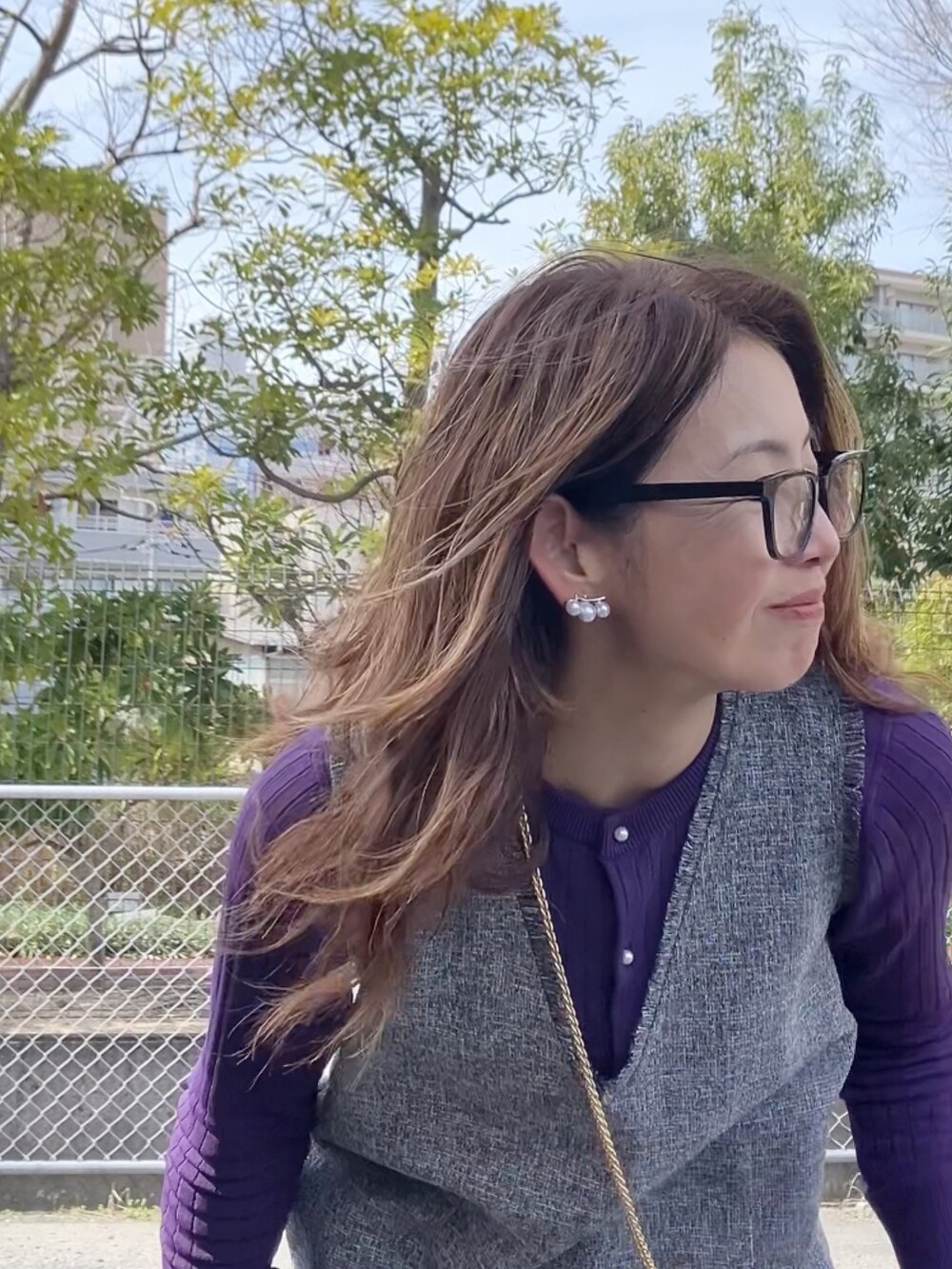 グレー系のワンピース、ホワイト系のハンドバッグ、ホワイト系のスニーカーを着用したレディースの冬コーディネートの3枚目の写真