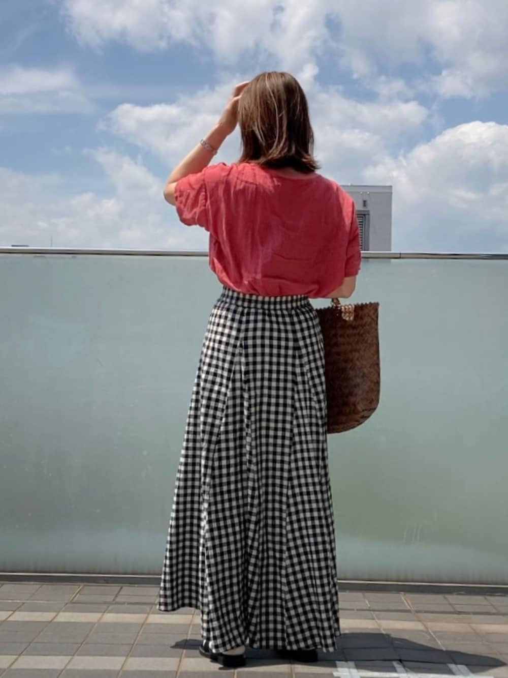 レッド系のトップス、ブラック系のスカート、ブラック系のスウェットを着用したレディースの春コーディネートの3枚目の写真