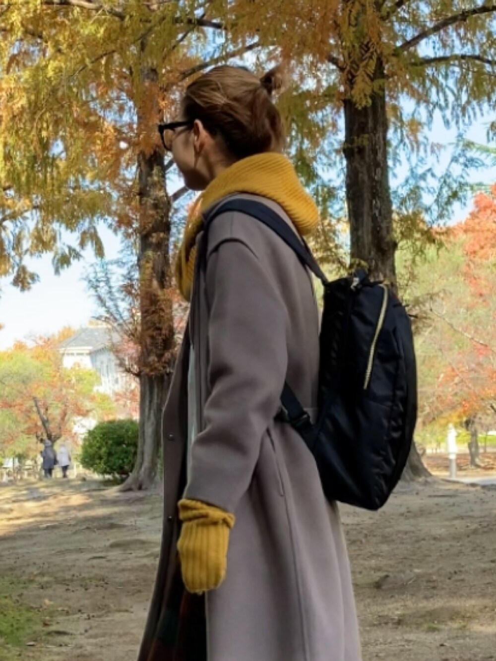 ブラウン系のチェスターコート、ブラック系のブーツ、ホワイト系のスウェットを着用したレディースの秋コーディネートの5枚目の写真