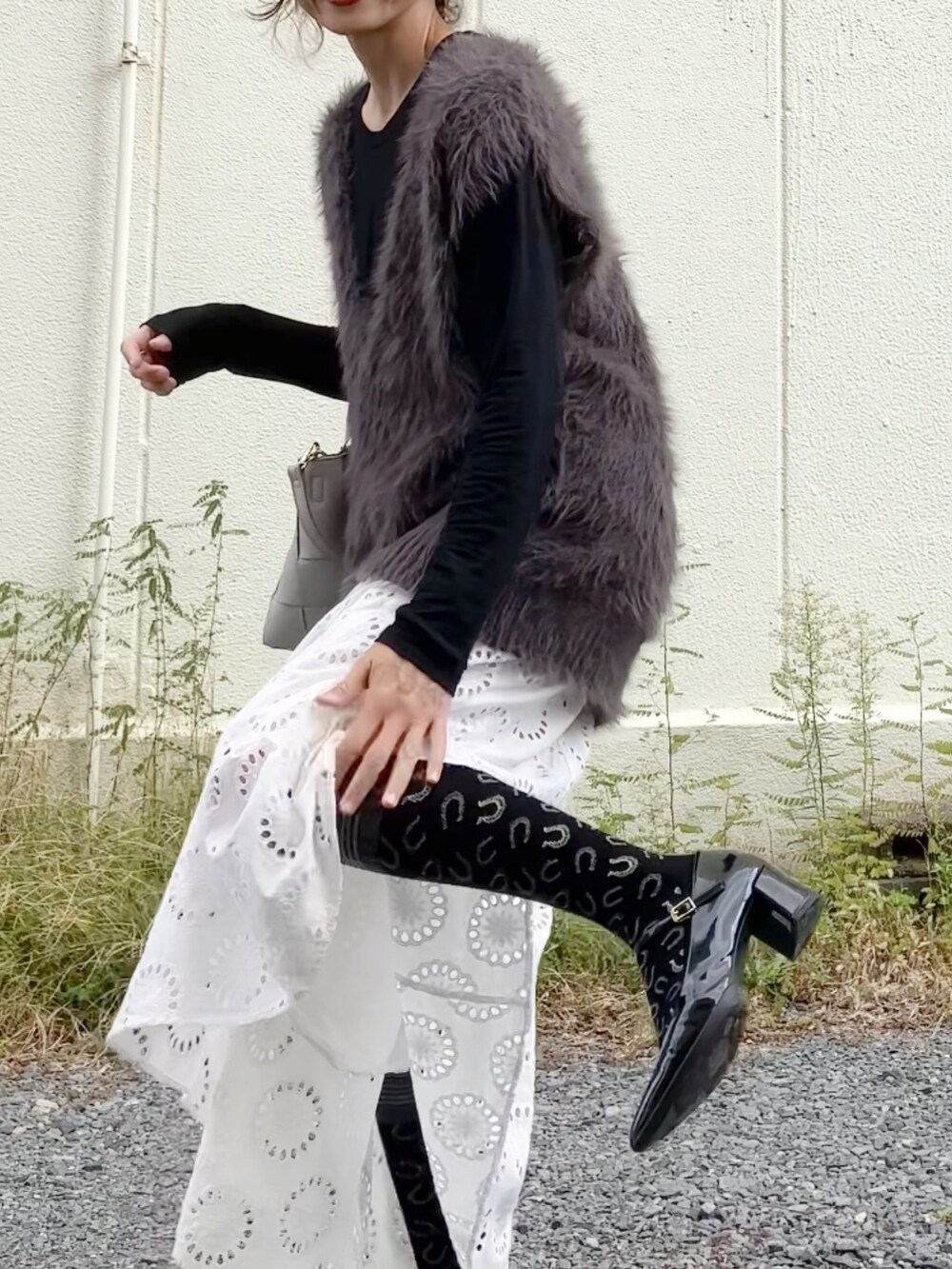 グレー系のニット/セーター、ブラック系のTシャツ/カットソー、グレー系のハンドバッグを着用したレディースの秋コーディネートの3枚目の写真