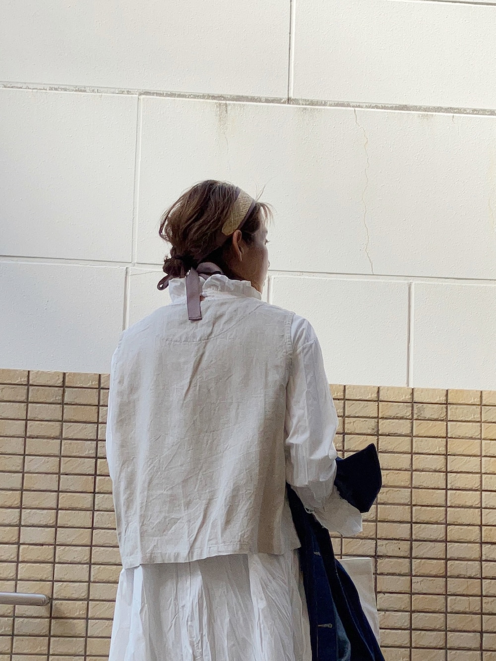 ベージュ系のベスト、ブルー系のデニムジャケット、ホワイト系のワンピースを着用したレディースの春コーディネートの4枚目の写真