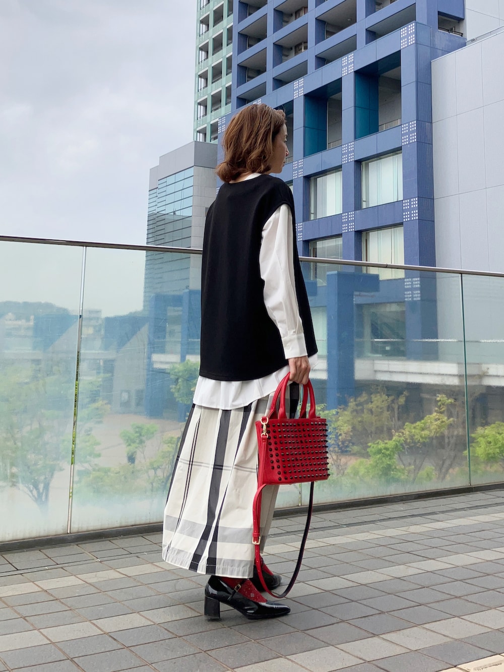 ホワイト系のシャツ/ブラウス、ブラック系のベスト、ホワイト系のスカートを着用したレディースの春コーディネートの2枚目の写真