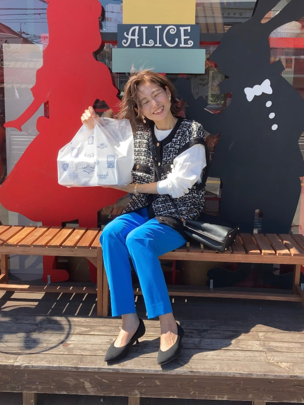 ブラック系のベスト、ブルー系のその他パンツ、ブラック系のハンドバッグを着用したレディースの秋コーディネートの2枚目の写真