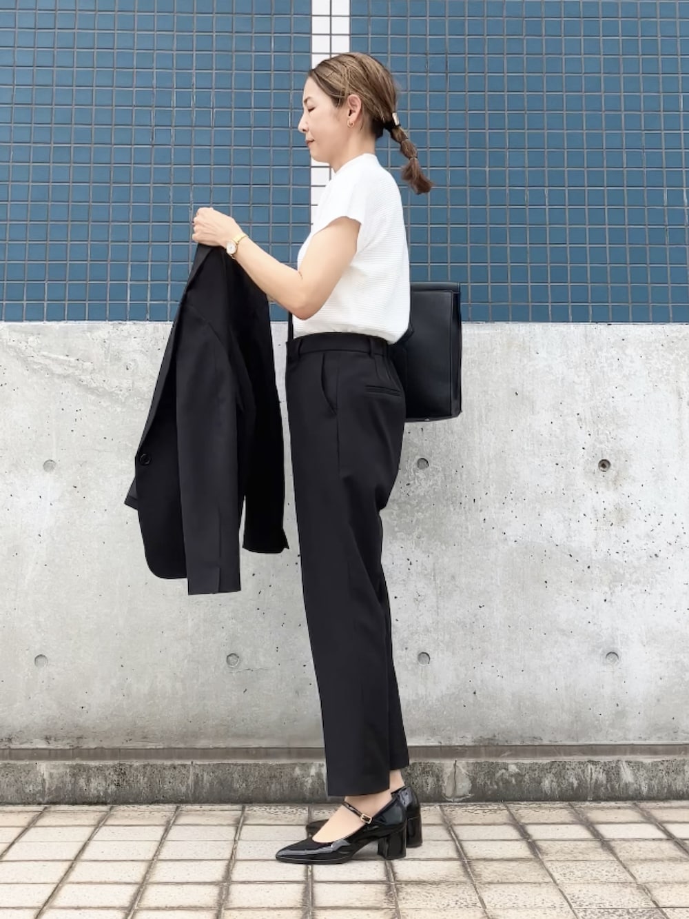 ブラック系のスーツセット、ホワイト系のTシャツ/カットソー、ブラック系のビジネスバッグを着用したレディースの夏コーディネートの4枚目の写真