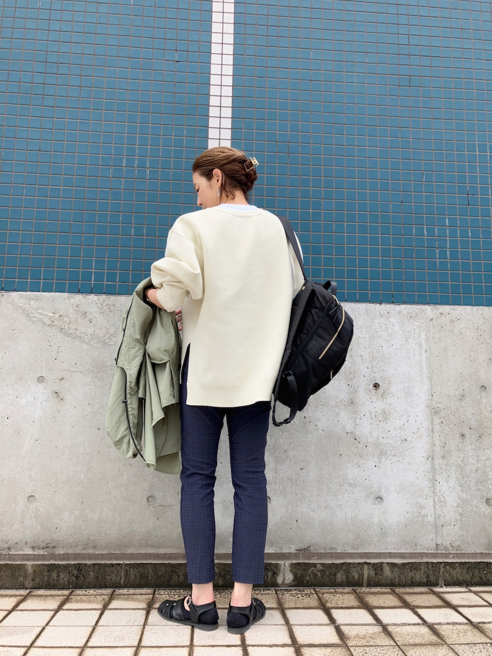 ブルー系のパンツ、ホワイト系のニット/セーター、ブラック系のサンダルを着用したレディースの春コーディネートの3枚目の写真