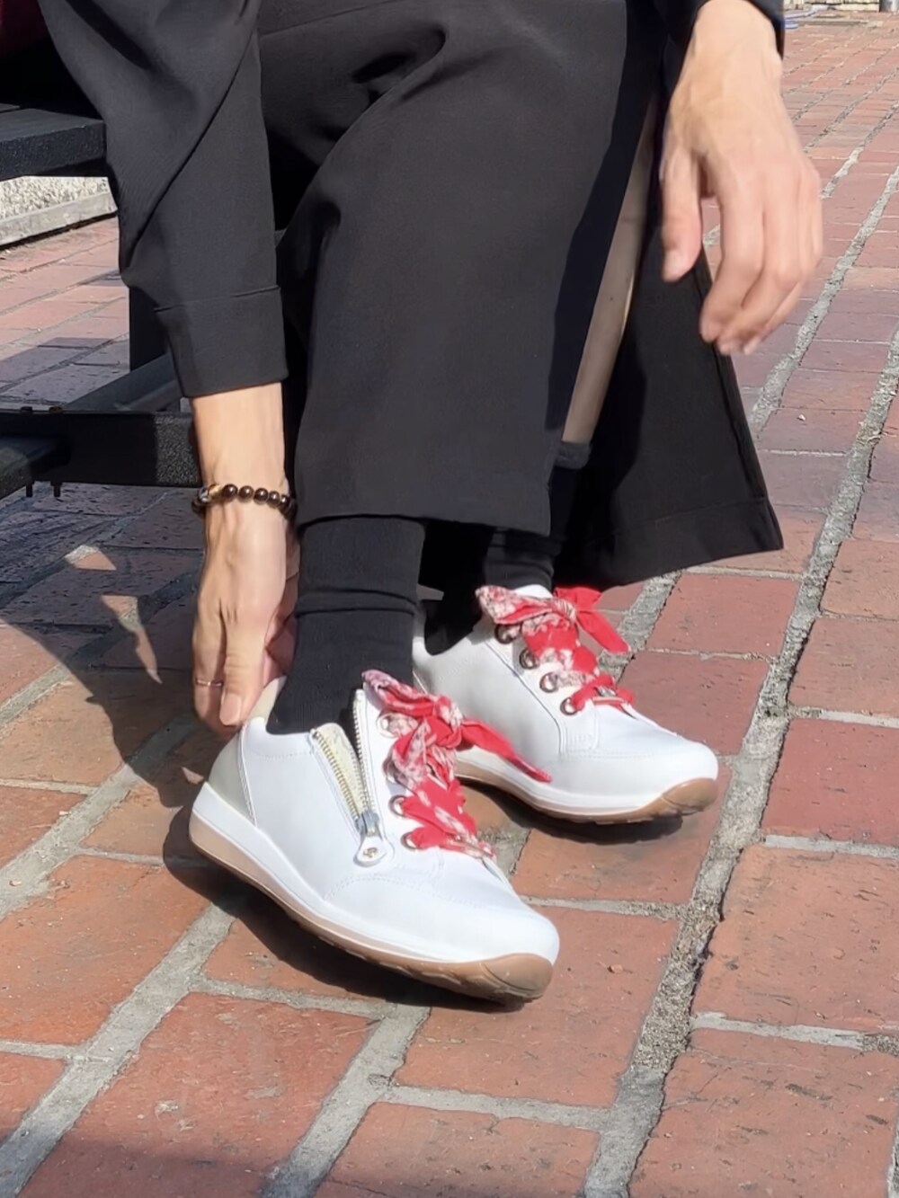 ホワイト系のスニーカー、レッド系のボストンバッグ、ブラック系のシャツワンピースを着用したレディースの秋コーディネートの4枚目の写真