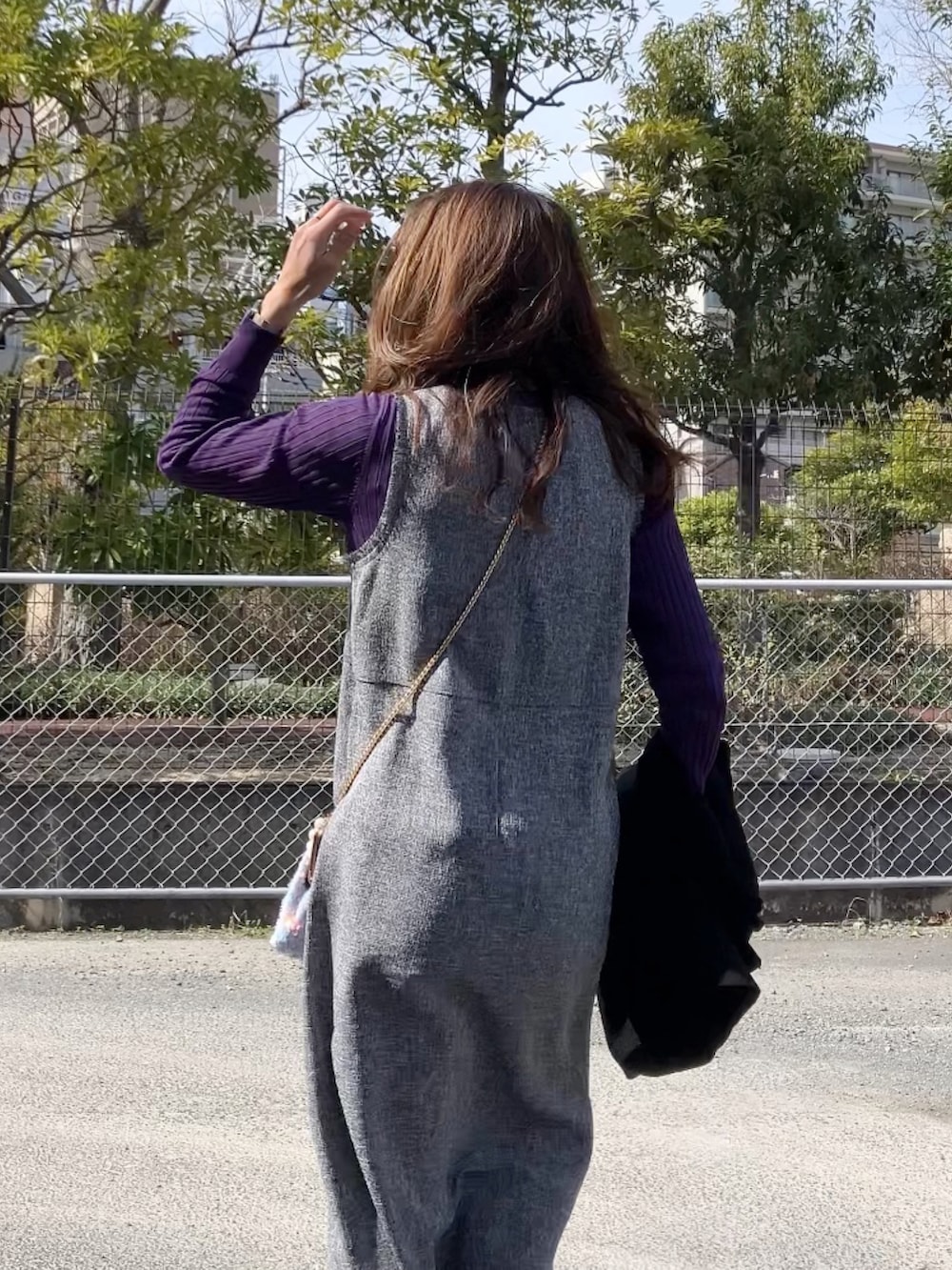 グレー系のワンピース、ホワイト系のハンドバッグ、ホワイト系のスニーカーを着用したレディースの冬コーディネートの4枚目の写真