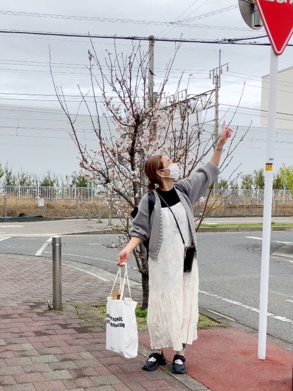 グレー系のカーディガン/ボレロ、ホワイト系のワンピース、ブラウン系のバックパック/リュックを着用したレディースの春コーディネートの2枚目の写真