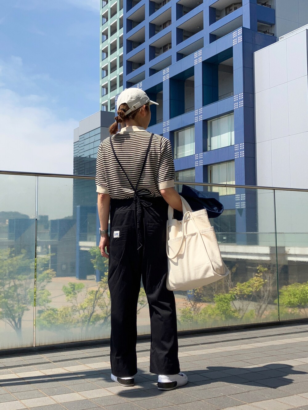 ブラック系のサロペット/オーバーオール、ブラック系のトップス、ブルー系のデニムジャケットを着用したレディースの春コーディネートの2枚目の写真