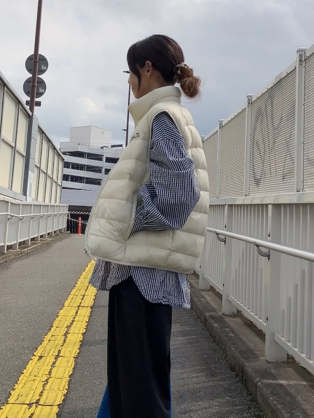 ホワイト系のダウンベスト、ブルー系のトートバッグを着用したレディースの秋コーディネートの2枚目の写真