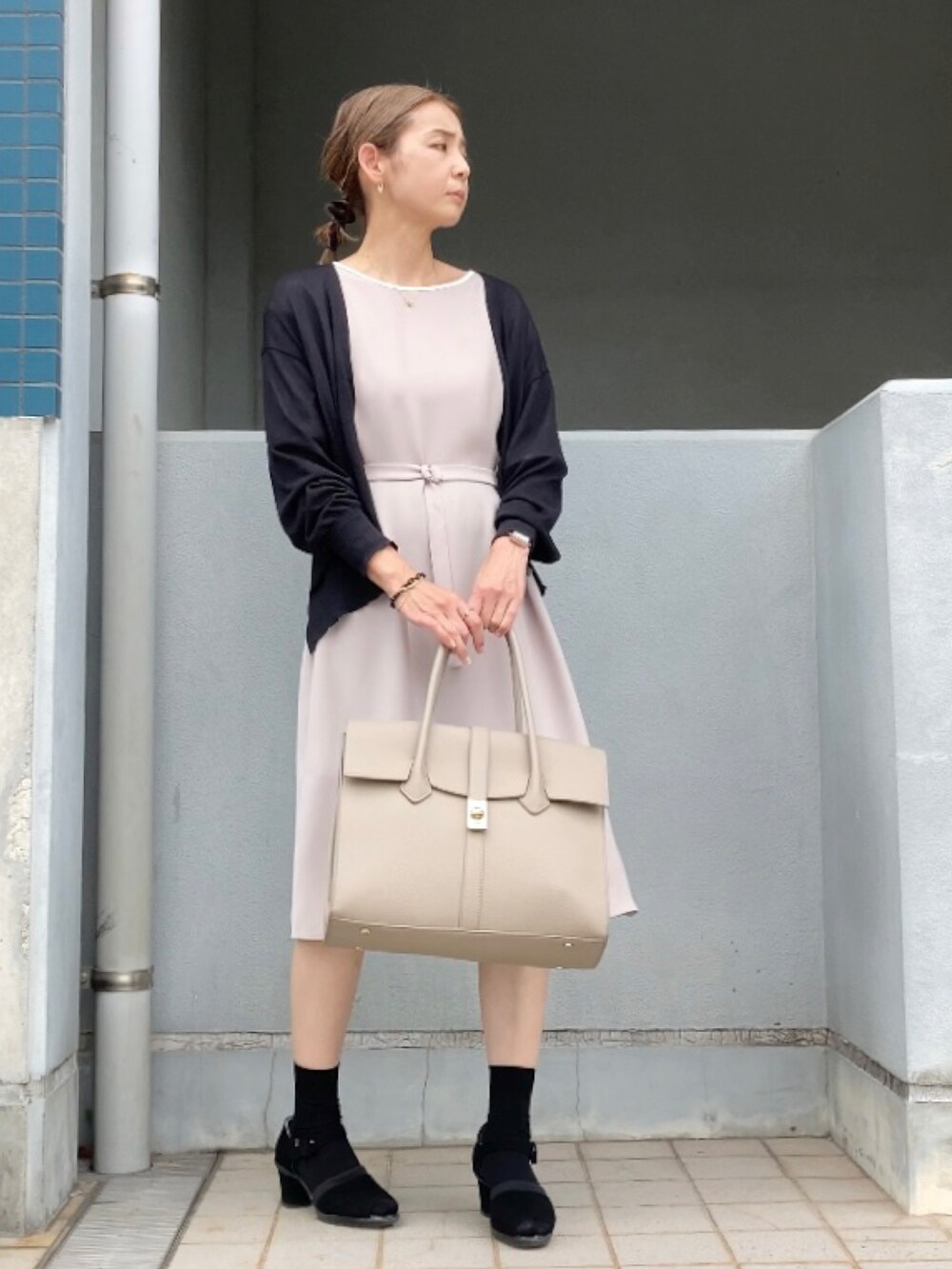 ベージュ系のワンピース、ベージュ系のビジネスバッグ、ブラック系のサンダルを着用したレディースの夏コーディネートの3枚目の写真