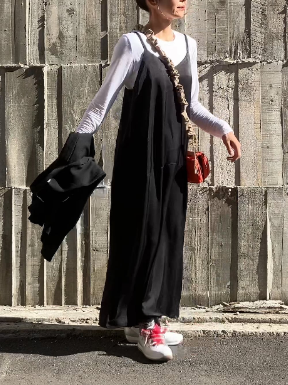 ブラック系のワンピース、オレンジ系のショルダーバッグ、ホワイト系のスニーカーを着用したレディースの冬コーディネートの4枚目の写真