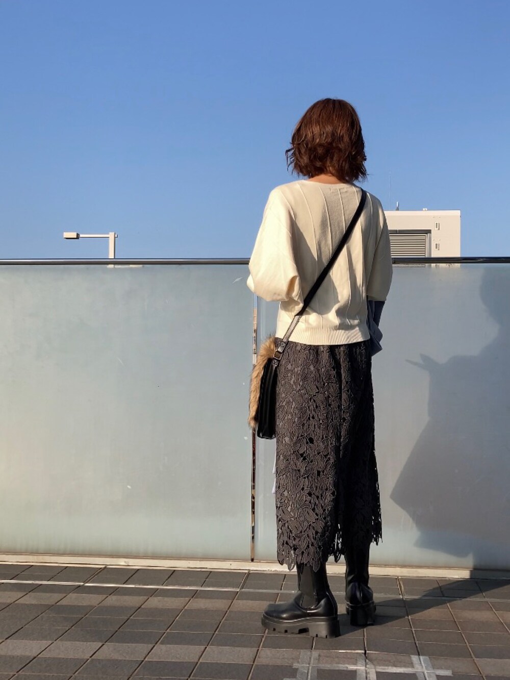 ホワイト系のニット/セーター、ブルー系のチェスターコート、ブラウン系のショルダーバッグを着用したレディースの秋コーディネートの3枚目の写真