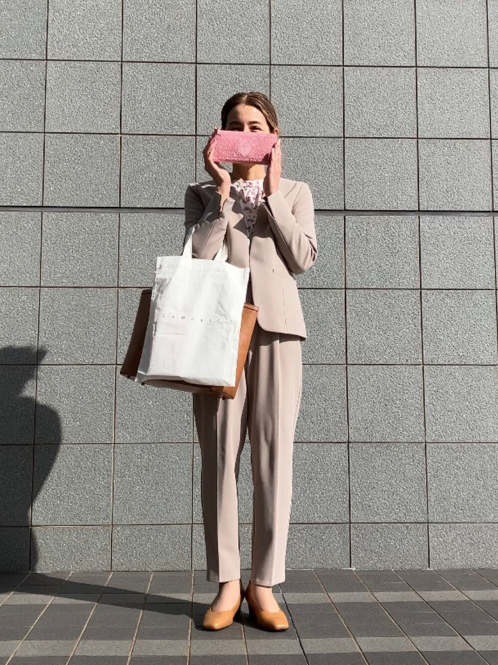 ベージュ系のスーツセット、ベージュ系のパンプス、ブラウン系のバッグを着用したレディースの冬コーディネートの5枚目の写真