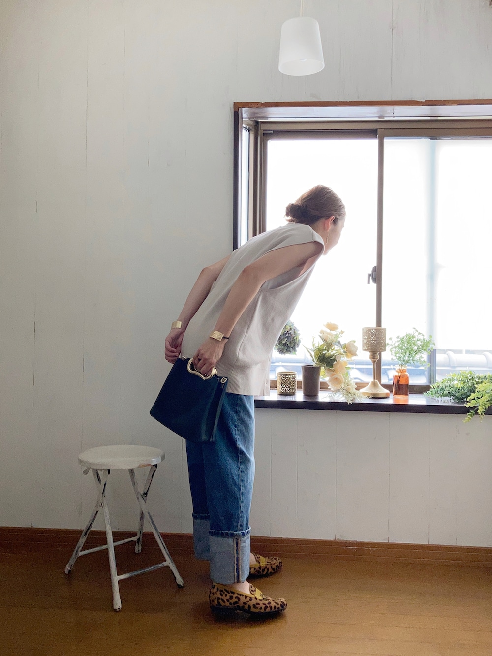 ベージュ系のベスト、ブラック系のハンドバッグ、ブルー系のデニムパンツを着用したレディースの夏コーディネートの2枚目の写真