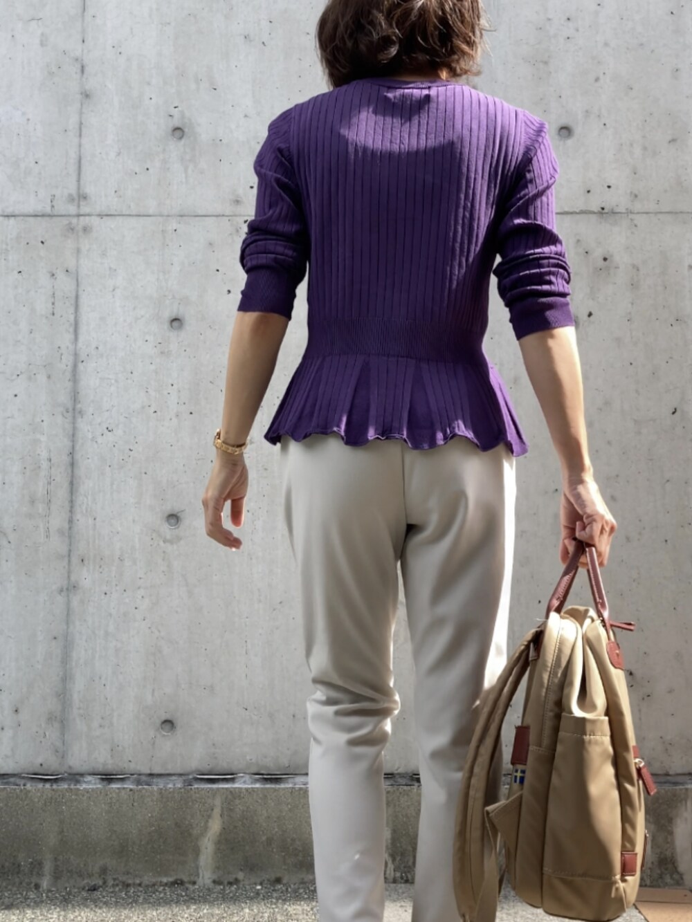 パープル系のカーディガン/ボレロ、ホワイト系のパンツ、ベージュ系のバックパック/リュックを着用したレディースの秋コーディネートの2枚目の写真