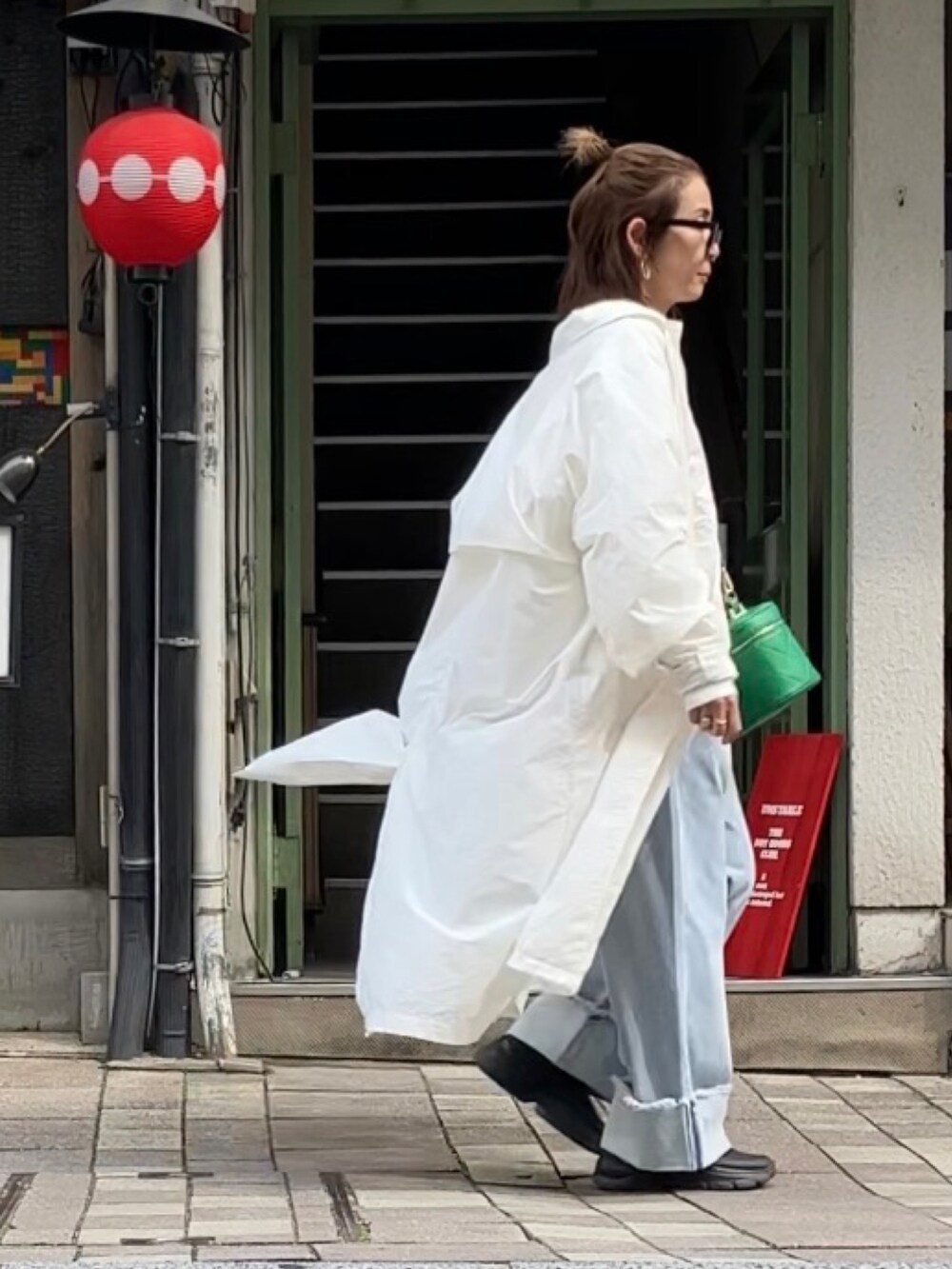 ホワイト系のスウェット、ブルー系のデニムパンツ、グリーン系のショルダーバッグを着用したレディースの春コーディネートの2枚目の写真