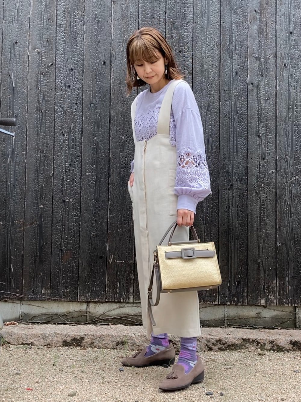 グレー系のハンドバッグ、パープル系のシャツ/ブラウス、ベージュ系のジャンパースカートを着用したレディースの春コーディネートの3枚目の写真