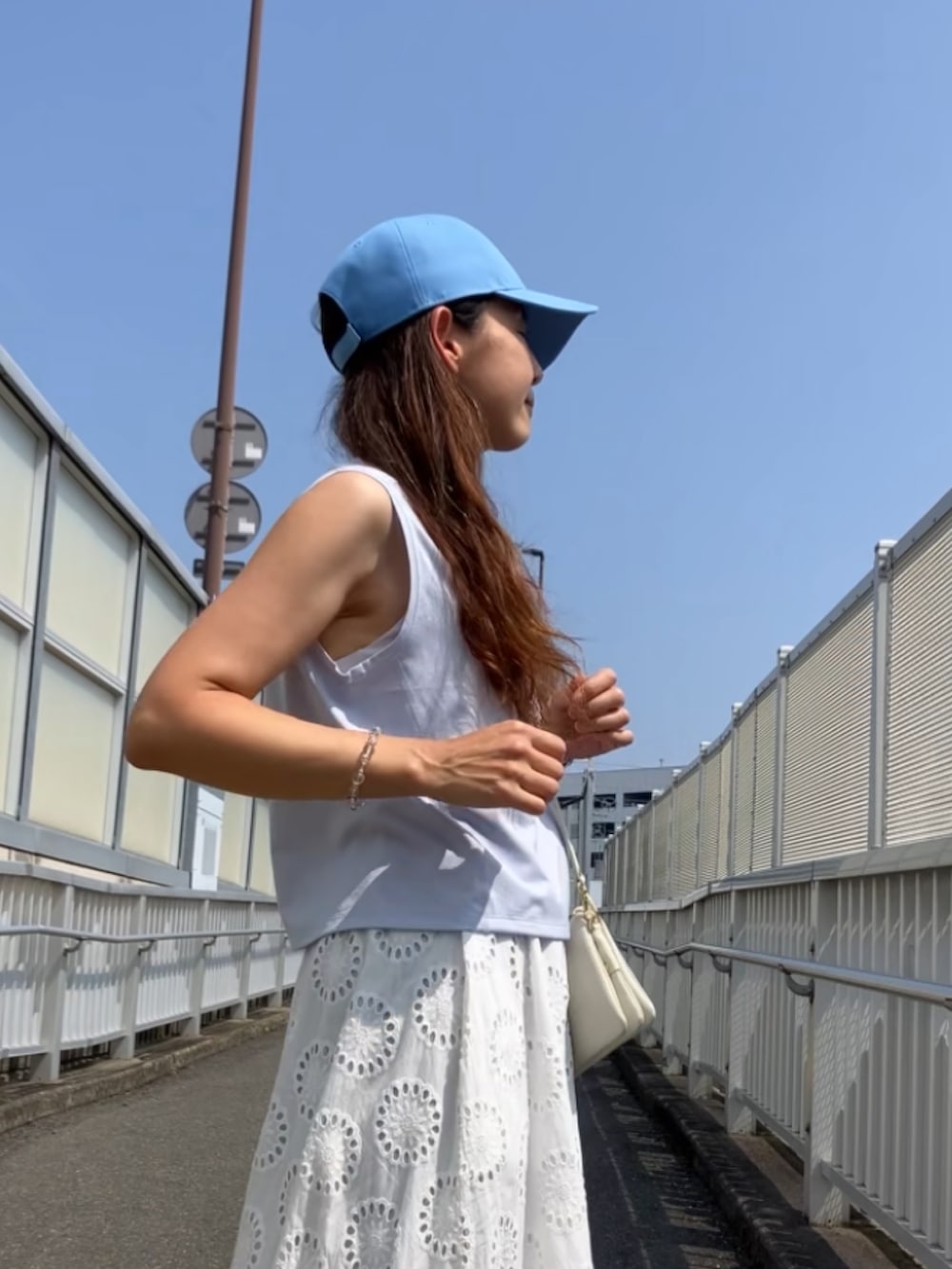 ホワイト系のショルダーバッグ、ブルー系のキャップを着用したレディースの夏コーディネートの2枚目の写真