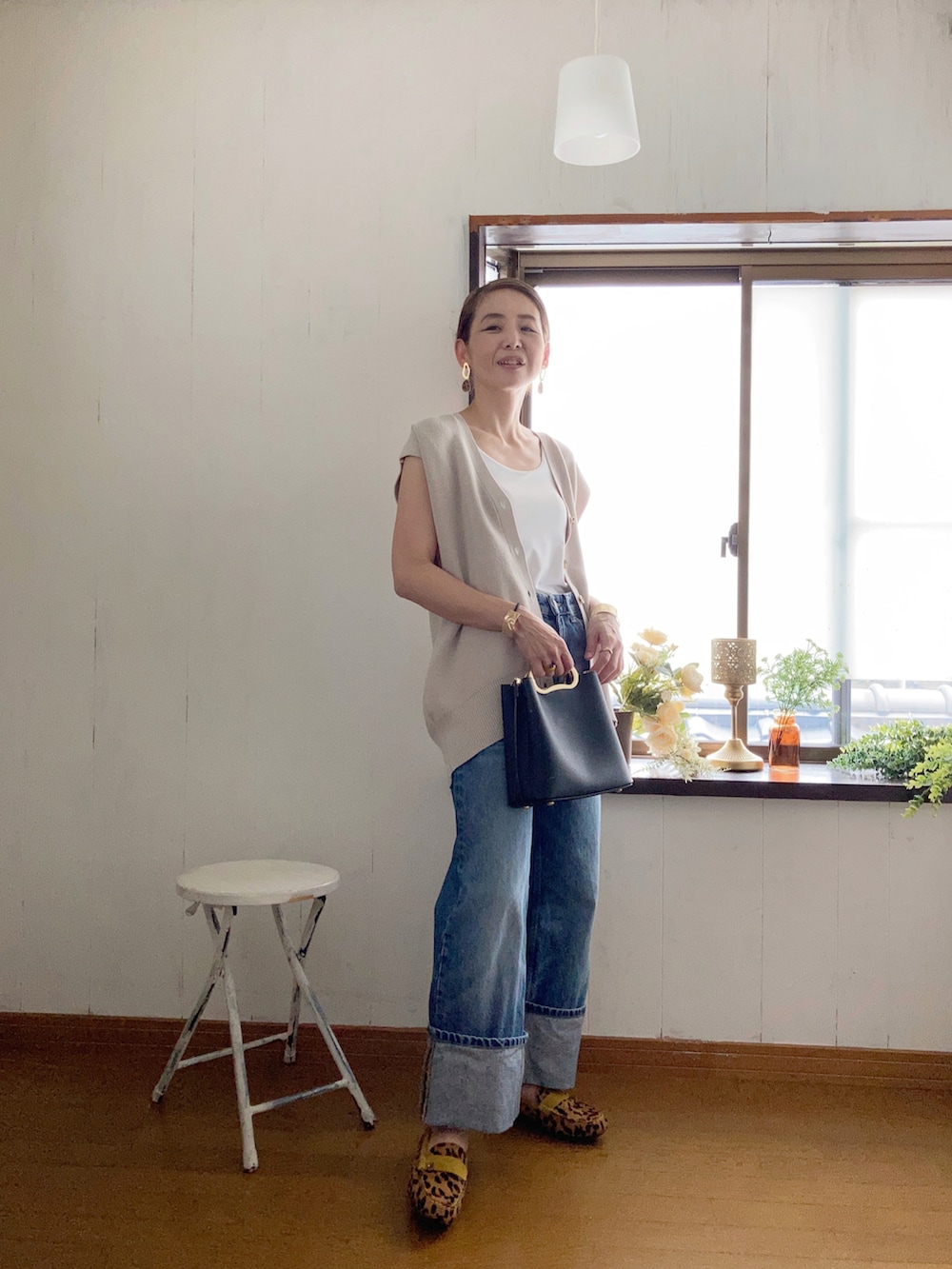 ベージュ系のベスト、ブラック系のハンドバッグ、ブルー系のデニムパンツを着用したレディースの夏コーディネートの3枚目の写真